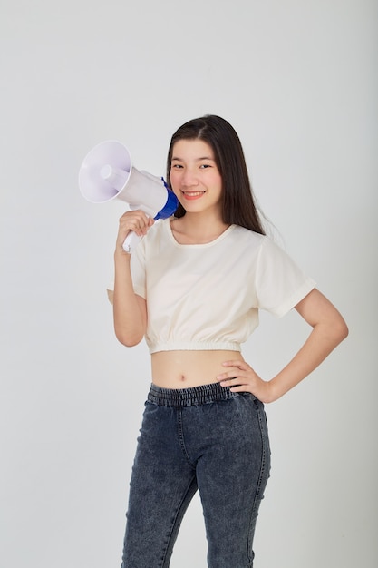 Retrato hermosa mujer asiática joven sonrisa con megáfono haciendo anuncio en estudio aislado