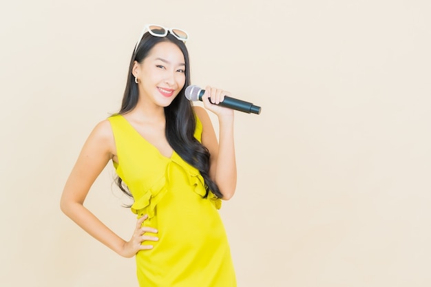 Retrato hermosa mujer asiática joven sonrisa con micrófono para cantar en la pared