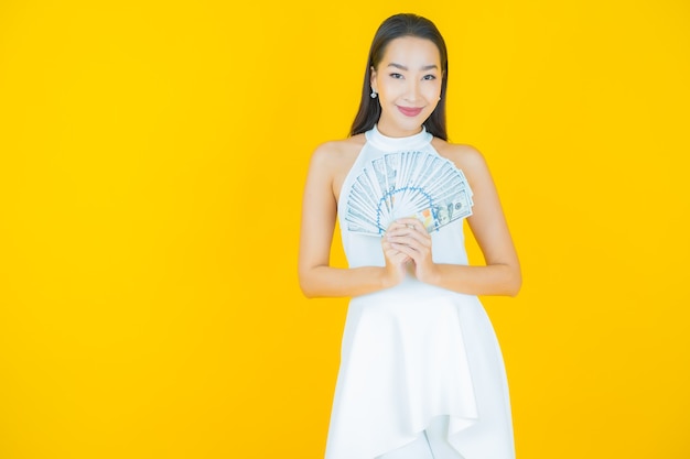 Retrato hermosa mujer asiática joven sonrisa con mucho dinero en efectivo y dinero en amarillo