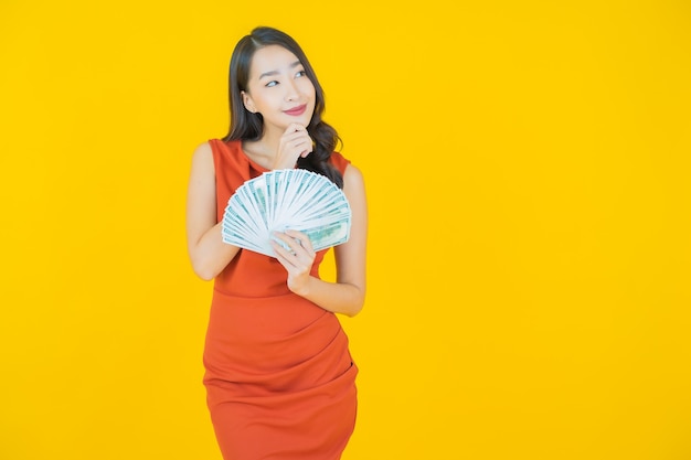 Retrato hermosa mujer asiática joven sonrisa con mucho dinero en efectivo y dinero en amarillo