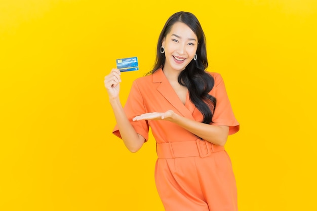 Retrato hermosa mujer asiática joven sonrisa con tarjeta de crédito en amarillo