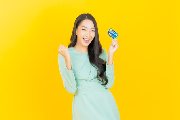 Retrato hermosa mujer asiática joven sonrisa con tarjeta de crédito en amarillo