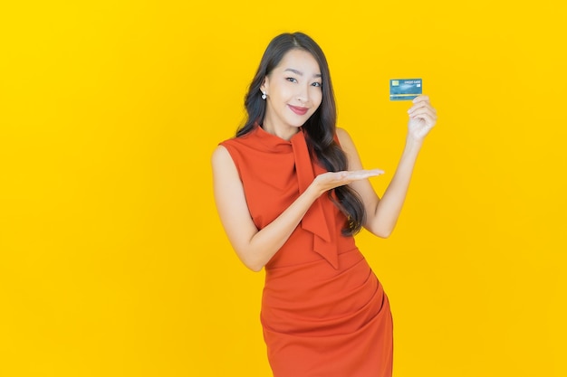 Retrato hermosa mujer asiática joven sonrisa con tarjeta de crédito en amarillo