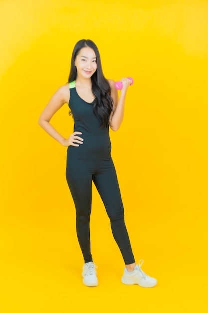 Retrato de hermosa mujer asiática joven con traje de gimnasia sosteniendo pesas