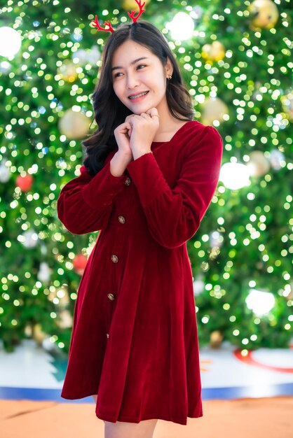 Retrato de hermosa mujer asiática joven vestido rojo traje y decoración de paquete de imagen de saludo de Navidad sobre fondo de luz de árbol de Navidad circular bokeh Decoración durante Navidad y año nuevo.