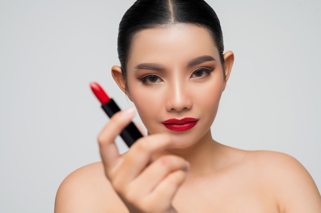 Retrato de hermosa mujer asiática con lápiz labial en la mano