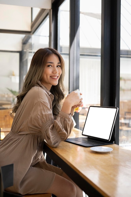 Retrato de una hermosa mujer asiática sentada en una oficina brillante y sonriendo a la cámara