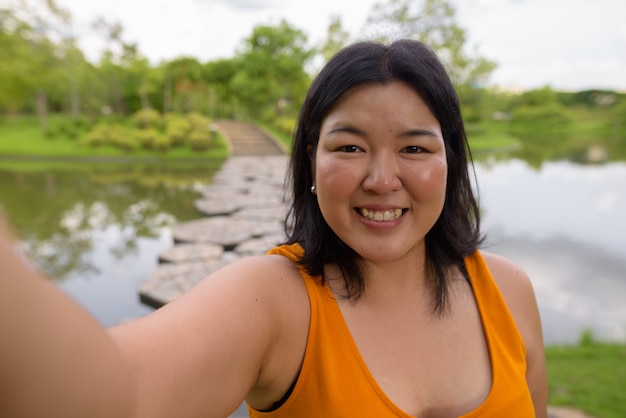 Retrato de hermosa mujer asiática con sobrepeso relajándose en el parque de la ciudad de Bangkok, Tailandia