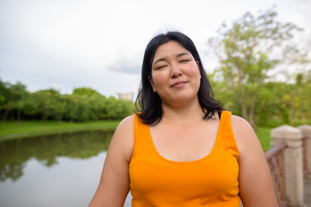 Retrato de hermosa mujer asiática con sobrepeso relajándose en el parque de la ciudad de Bangkok, Tailandia