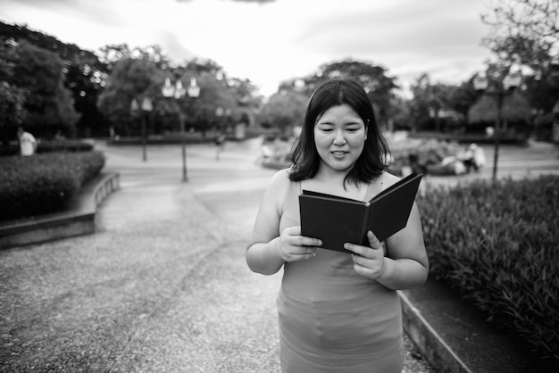 Retrato de hermosa mujer asiática con sobrepeso relajante en el parque de la ciudad en blanco y negro