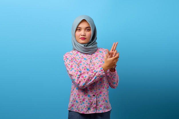 Retrato de hermosa mujer asiática sosteniendo una pistola simbólica con gesto de mano