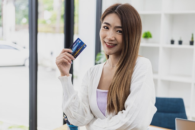 Retrato de una hermosa mujer asiática sosteniendo una tarjeta de crédito, concepto de compras en línea pagando con tarjeta de crédito, mujer de negocios asiática joven, ejecutiva femenina moderna, líder empresarial.