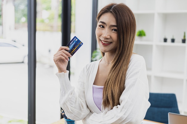 Foto retrato de una hermosa mujer asiática sosteniendo una tarjeta de crédito, concepto de compras en línea pagando con tarjeta de crédito, mujer de negocios asiática joven, ejecutiva femenina moderna, líder empresarial.