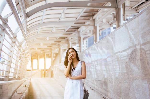 Retrato de una hermosa mujer asiática usando un celular y caminando por la ciudad