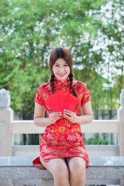 Retrato de hermosa mujer asiática en vestido Cheongsam con sobre rojo en la manoGente de TailandiaFeliz concepto de año nuevo chino