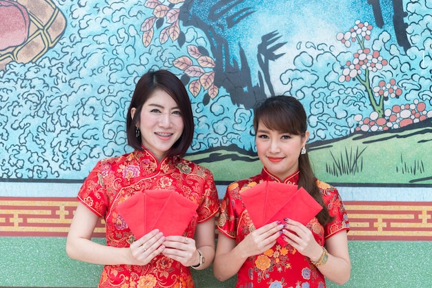 Retrato de hermosa mujer asiática en vestido Cheongsam con sobre rojo en la manoGente de TailandiaFeliz concepto de año nuevo chino