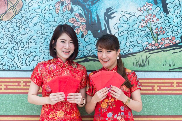 Retrato de hermosa mujer asiática en vestido Cheongsam con sobre rojo en la manoGente de TailandiaFeliz concepto de año nuevo chino