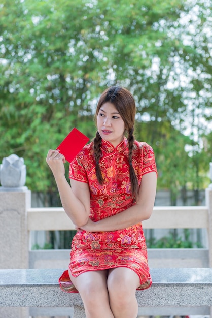 Retrato de hermosa mujer asiática en vestido Cheongsam con sobre rojo en la manoGente de TailandiaFeliz concepto de año nuevo chino