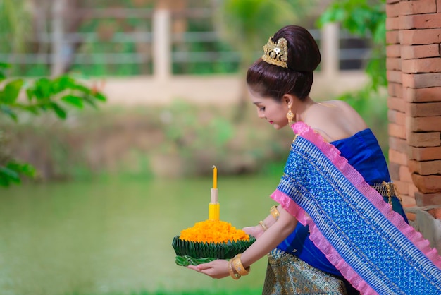 Retrato de hermosa mujer asiática en vestido tailandés tradicional orando mantenga kratong para unirse al festival loy kratong en tailandia