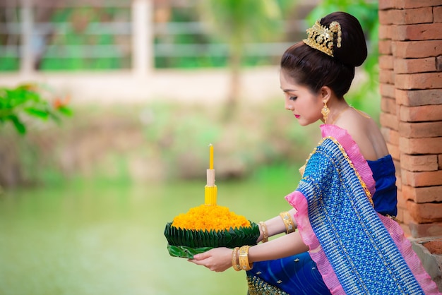 Retrato de hermosa mujer asiática en vestido tailandés tradicional orando mantenga kratong para unirse al festival loy kratong en tailandia