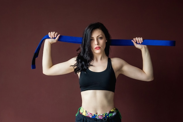 Foto retrato hermosa mujer atlética con cinturón azul en el fondo de la pared concepto de artes marciales