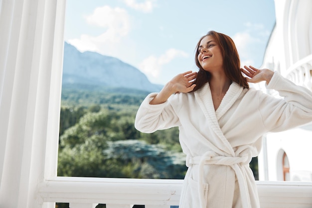 Retrato de una hermosa mujer de cabello largo con una bata blanca en el balcón de un hotel Mountain View