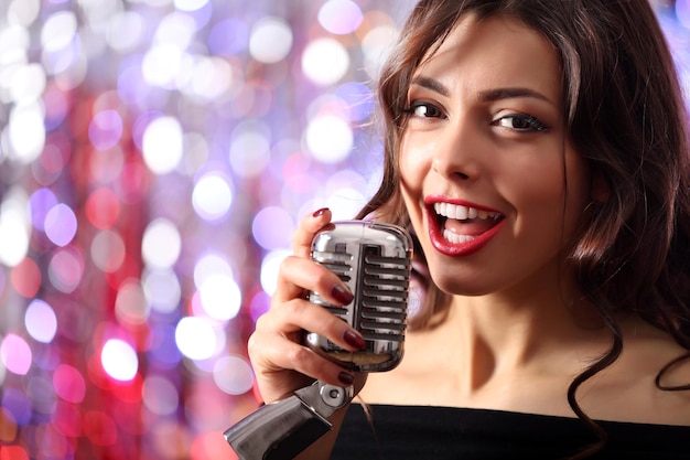 Foto retrato de una hermosa mujer cantando contra un fondo de brillo brillante