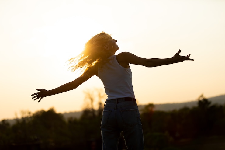 Retrato de hermosa mujer caucásica sonriendo y mirando a otro lado en el parque. Feliz youn femal en la puesta de sol en la naturaleza con las manos abiertas