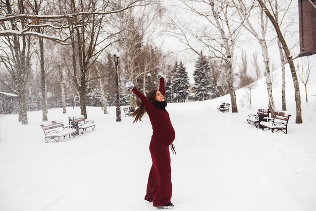 Retrato de hermosa mujer embarazada en el parque de invierno.