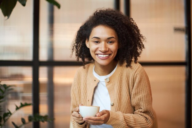 Retrato de una hermosa mujer de éxito segura con una taza de café sonriendo mirando a la cámara