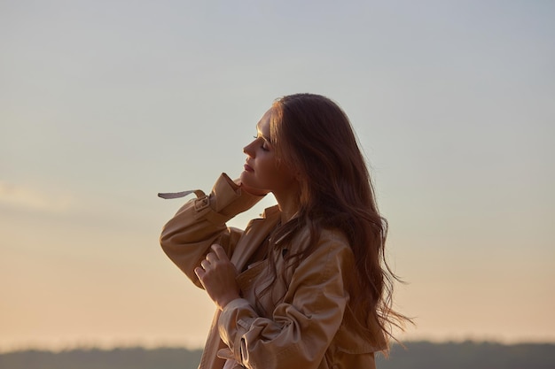 Retrato de una hermosa mujer joven al atardecer Mujer de pelo largo de belleza natural en un impermeable