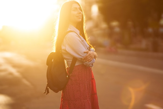 Retrato de hermosa mujer joven al atardecer Niña disfruta del sol en una calle de la ciudad