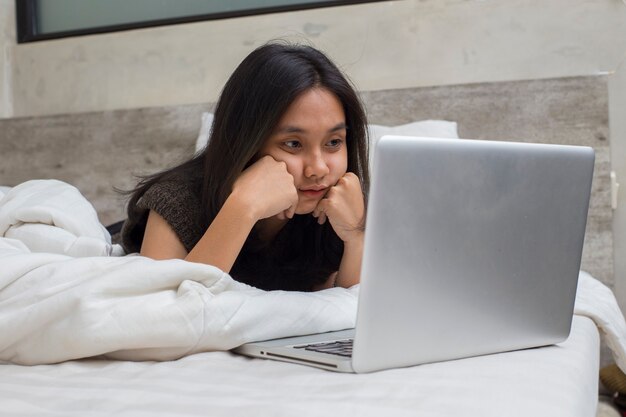 Retrato de hermosa mujer joven asiática con ordenador portátil en la sala de estar en casa aislado en blanco