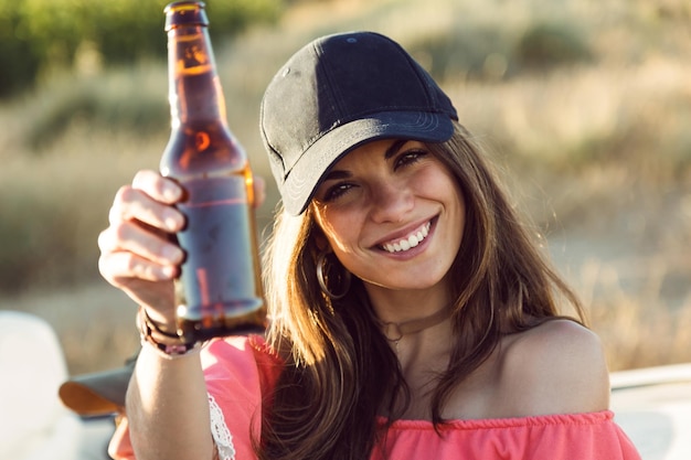 Retrato de hermosa mujer joven bebiendo cerveza y disfrutando del día de verano.