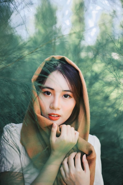Retrato de una hermosa mujer joven contra los árboles