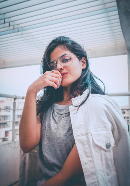 Foto retrato de una hermosa mujer joven con gafas mientras está sentada en el techo