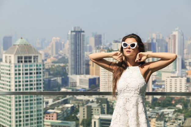 Foto retrato de hermosa mujer joven con gafas de sol en la ciudad grande y moderna