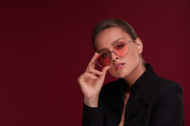 Retrato de hermosa mujer joven con gafas de sol rojos. Modelo de moda sensual