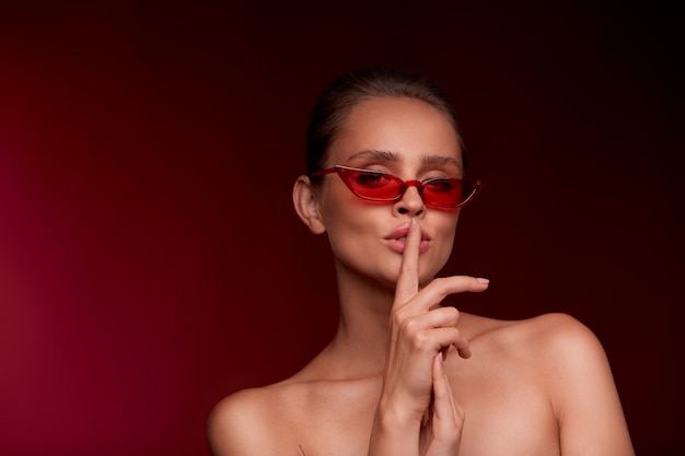 Retrato de hermosa mujer joven con gafas de sol rojos. Modelo de moda sensual