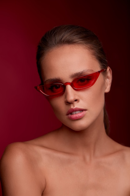 Retrato de hermosa mujer joven con gafas de sol rojos. Modelo de moda sensual