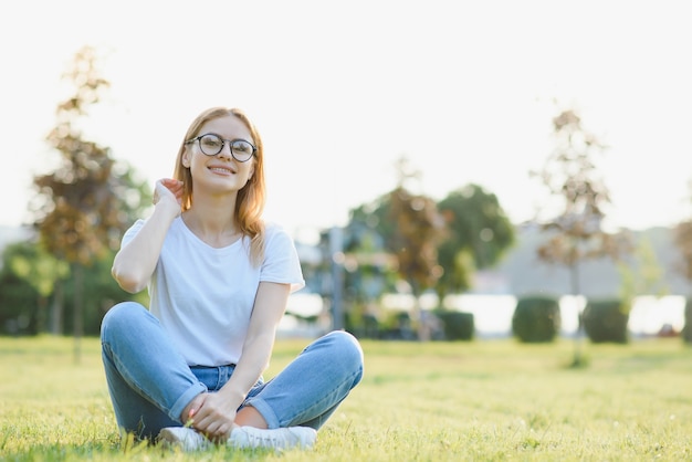 Retrato de una hermosa mujer joven o niña en una pradera muy verde viendo la puesta de sol disfrutando de la naturaleza al aire libre las noches de verano Brillo Solar. Copie el espacio.