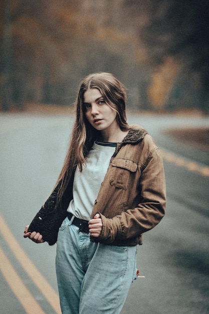 Retrato de una hermosa mujer joven de pie en la carretera