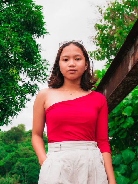 Foto retrato de una hermosa mujer joven de pie contra los árboles