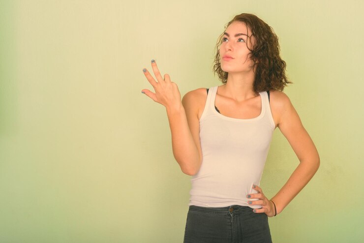 Foto retrato de una hermosa mujer joven de pie contra la pared