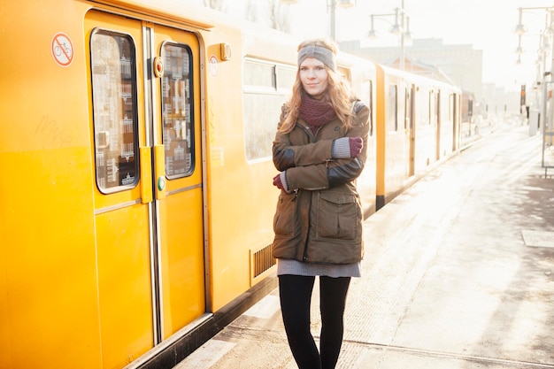 Retrato de una hermosa mujer joven de pie junto al tren amarillo durante el invierno