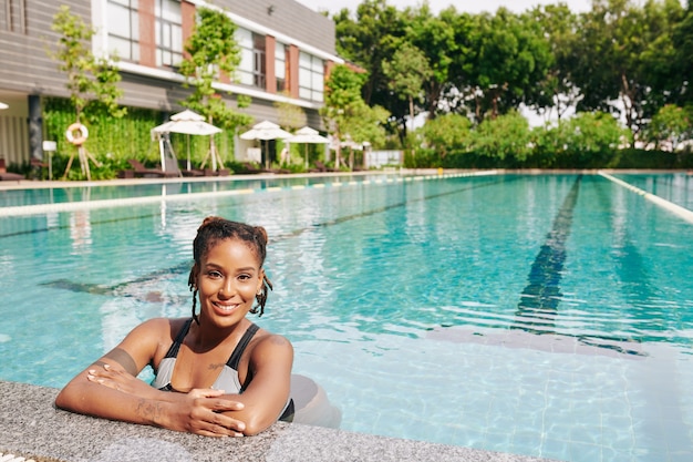 Retrato de hermosa mujer joven refrescante en la piscina del balneario en un caluroso día soleado