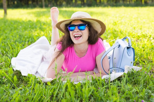 Retrato de hermosa mujer joven con sombrero y gafas de sol en el parque de picnic