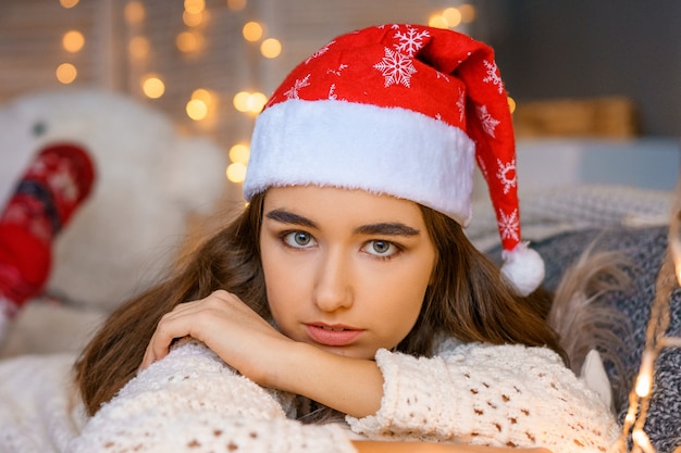 Retrato de hermosa mujer joven con sombrero de Santa Claus sobre fondo bokeh