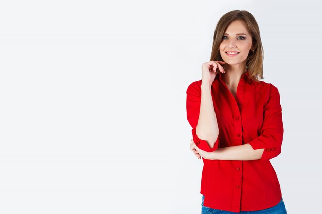 Retrato de hermosa mujer joven sonriente de pie en una camisa roja y jeans azul aislado