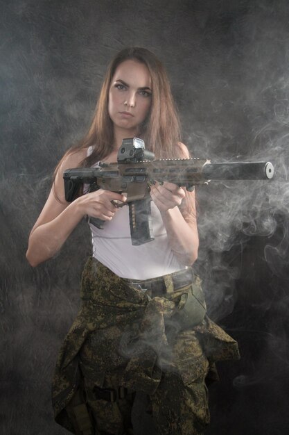 Foto retrato de una hermosa mujer joven sosteniendo una pistola mientras está de pie contra la pared